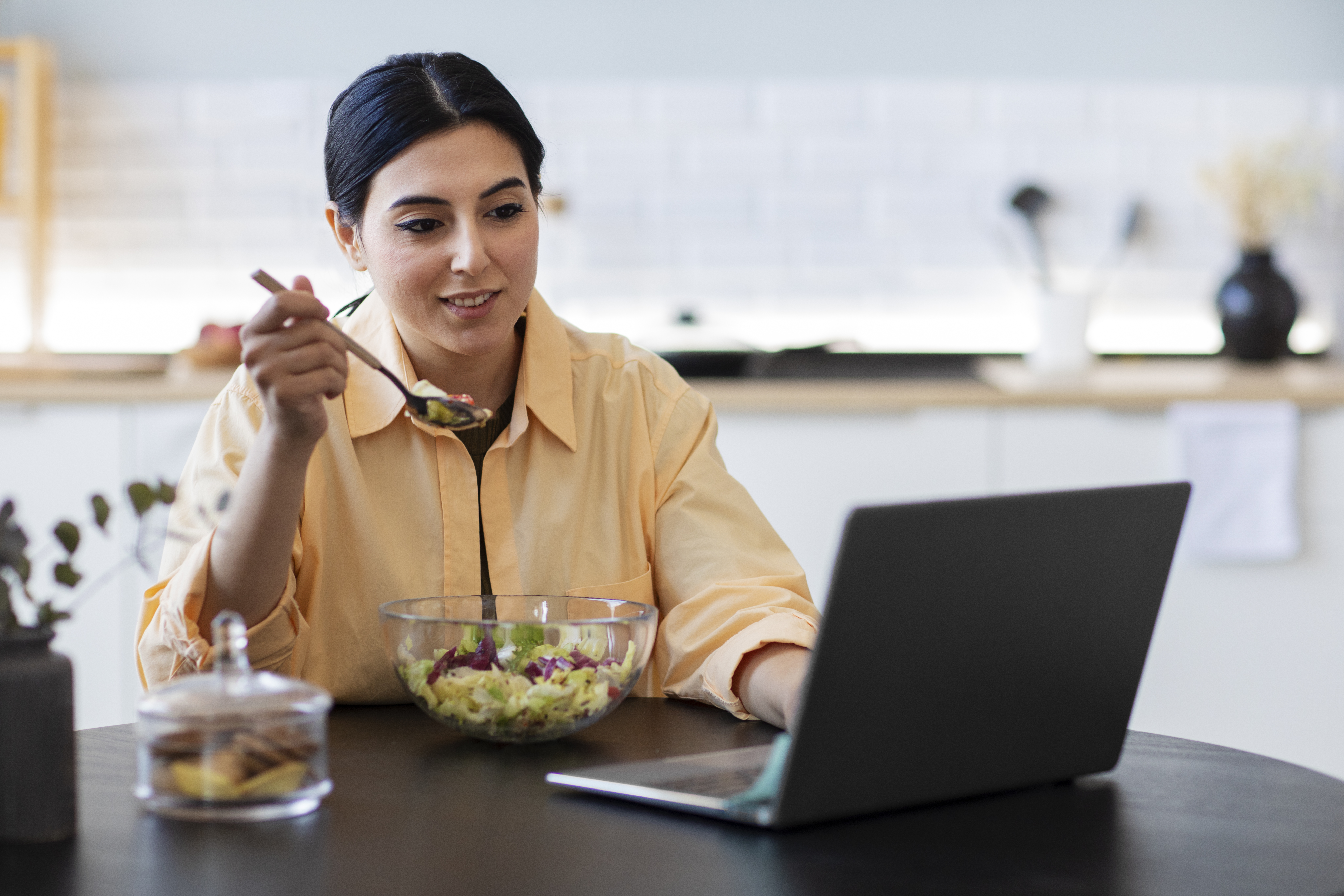 young-woman-eating-salad-while-engrossed-in-Laptop